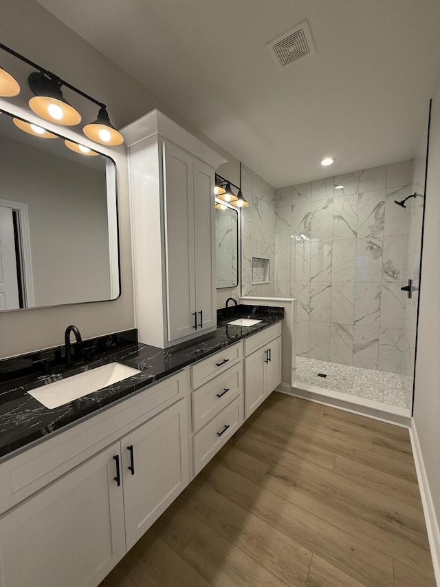 bathroom featuring hardwood / wood-style flooring, vanity, and tiled shower