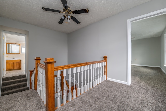 corridor with a textured ceiling and carpet floors