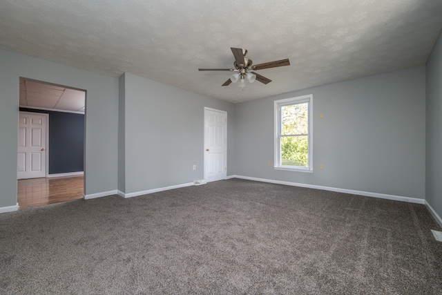 spare room with ceiling fan, a textured ceiling, and dark carpet