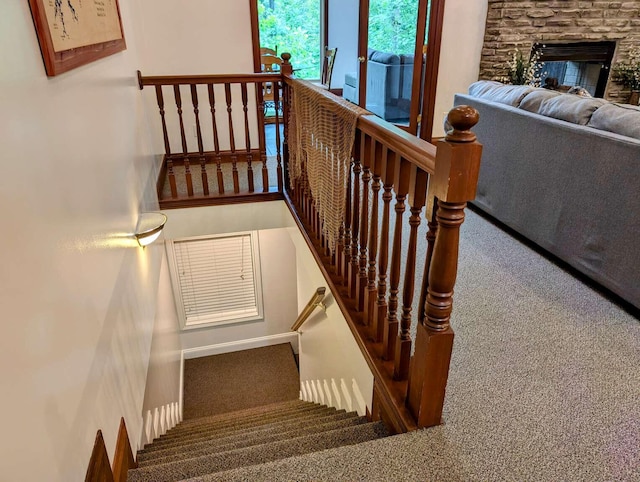 stairs featuring a stone fireplace and carpet floors