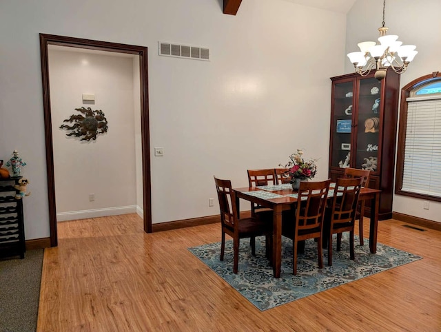 dining area with light hardwood / wood-style floors, lofted ceiling, and an inviting chandelier