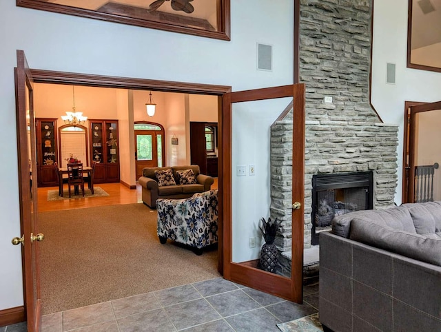 living room featuring a notable chandelier, carpet flooring, a high ceiling, and a fireplace