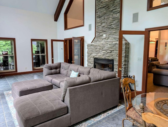 tiled living room with high vaulted ceiling, a stone fireplace, and beamed ceiling