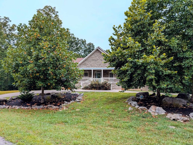 view of property hidden behind natural elements with a front yard and covered porch