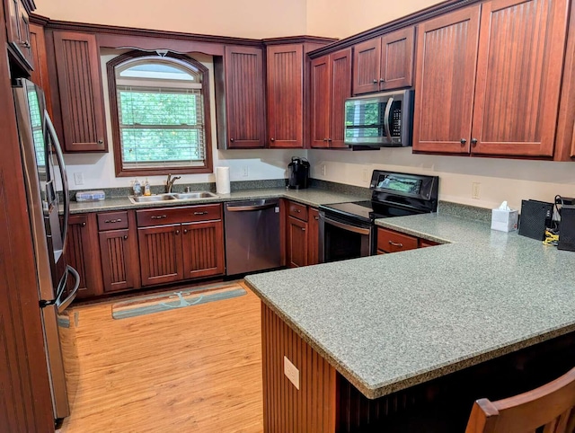 kitchen featuring light hardwood / wood-style flooring, appliances with stainless steel finishes, sink, and kitchen peninsula