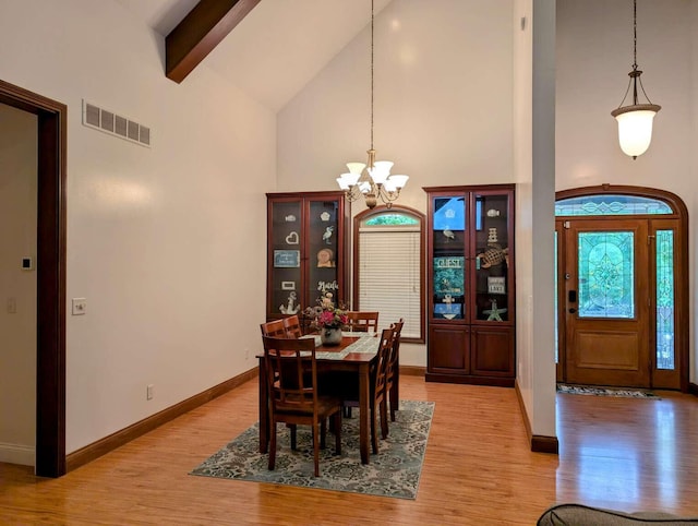 dining space featuring beamed ceiling, light hardwood / wood-style floors, a notable chandelier, and high vaulted ceiling