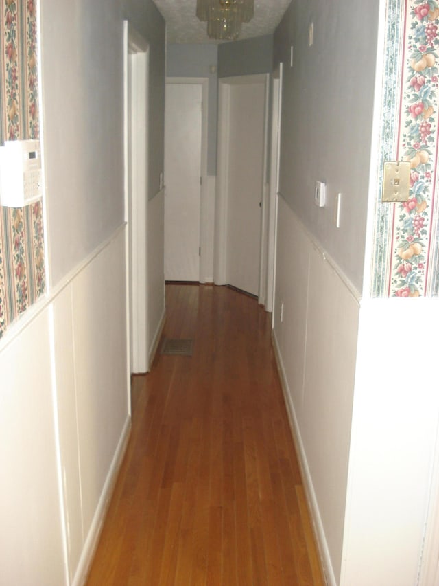 corridor with a notable chandelier and hardwood / wood-style floors