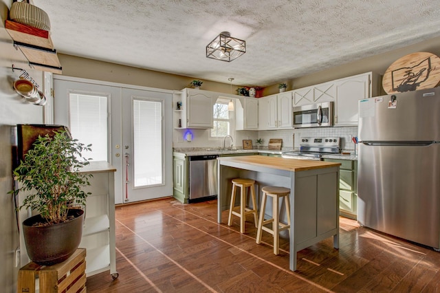 kitchen featuring white cabinets, stainless steel appliances, a kitchen island, and dark hardwood / wood-style floors