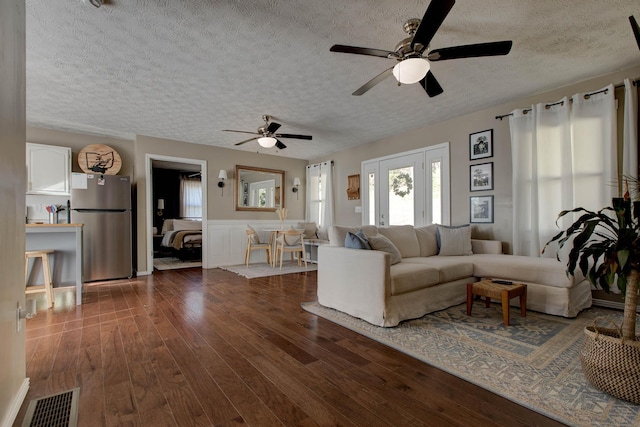 unfurnished living room featuring dark wood-type flooring, ceiling fan, and a textured ceiling