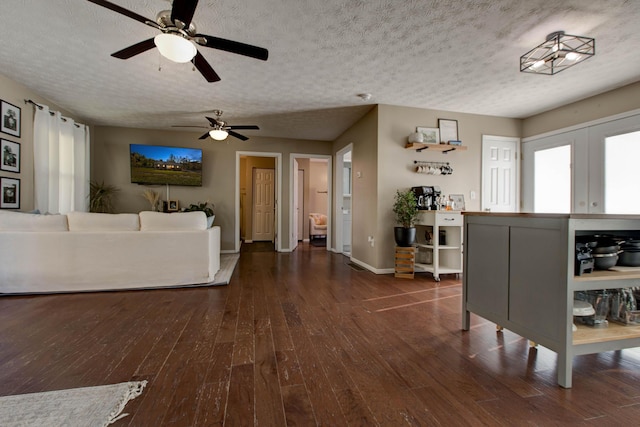 unfurnished living room featuring ceiling fan, a textured ceiling, and dark hardwood / wood-style floors