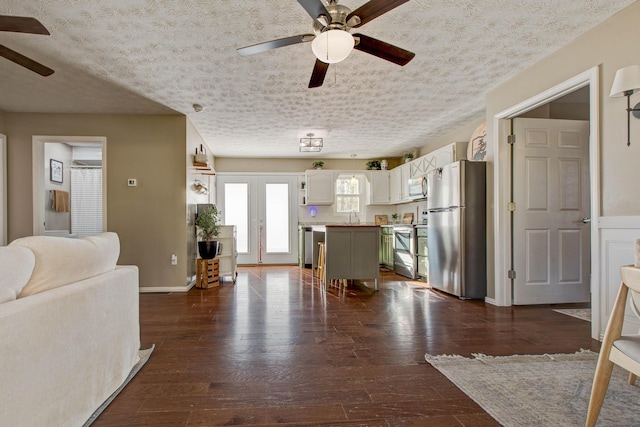 kitchen featuring appliances with stainless steel finishes, a center island, dark hardwood / wood-style flooring, white cabinetry, and a breakfast bar area