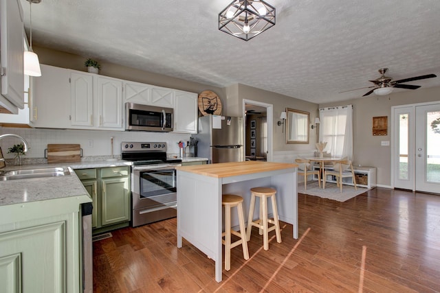 kitchen with a kitchen island, dark wood-type flooring, stainless steel appliances, sink, and pendant lighting