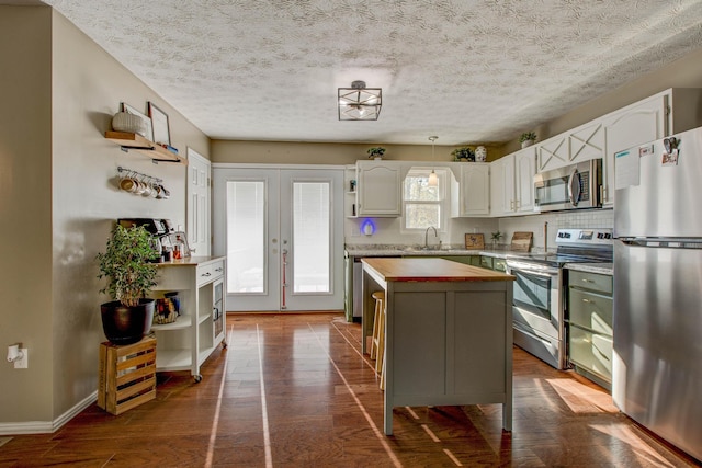 kitchen featuring dark wood-type flooring, appliances with stainless steel finishes, sink, a center island, and butcher block countertops