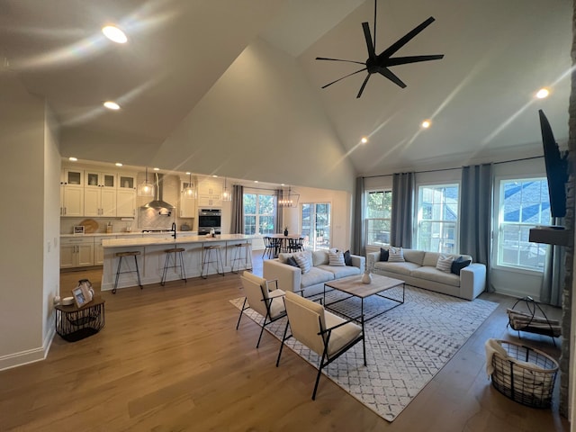 living room with high vaulted ceiling, light hardwood / wood-style flooring, and ceiling fan