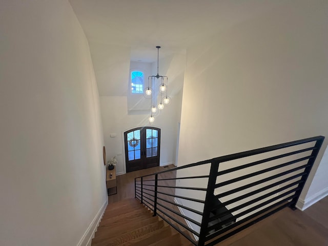 staircase featuring hardwood / wood-style floors, a chandelier, and french doors