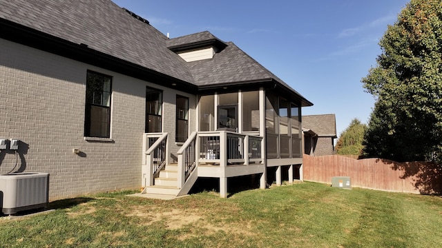 rear view of property with a lawn and cooling unit