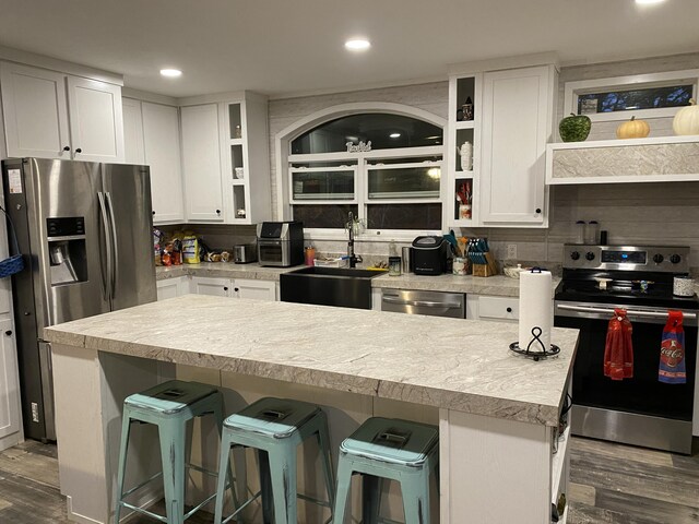 kitchen with a kitchen bar, appliances with stainless steel finishes, sink, white cabinets, and a center island