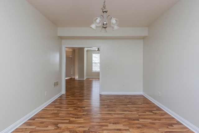 unfurnished dining area featuring wood-type flooring and ceiling fan with notable chandelier