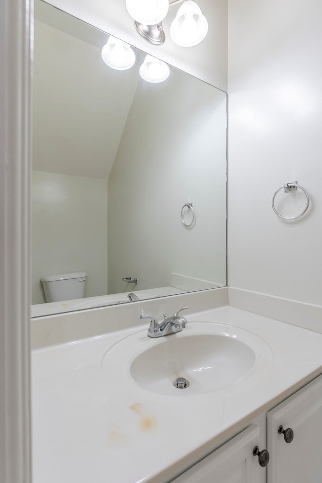 bathroom with toilet, lofted ceiling, and vanity