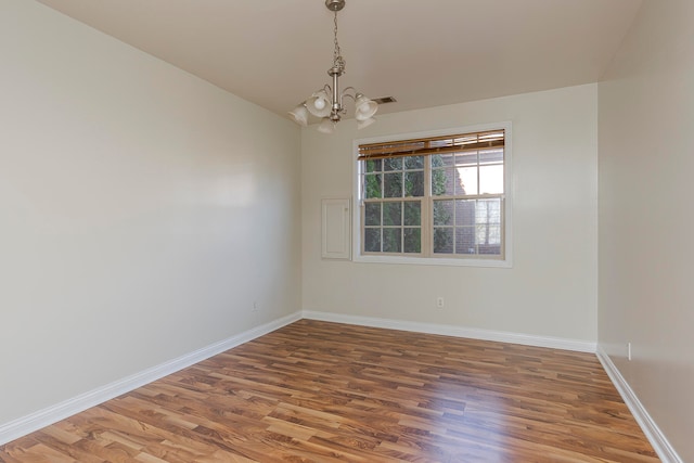 unfurnished room featuring lofted ceiling, hardwood / wood-style floors, and a chandelier