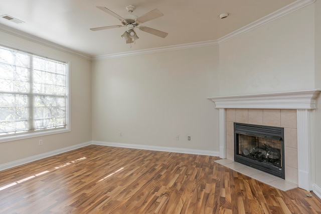 unfurnished living room featuring crown molding, a tiled fireplace, hardwood / wood-style flooring, and ceiling fan