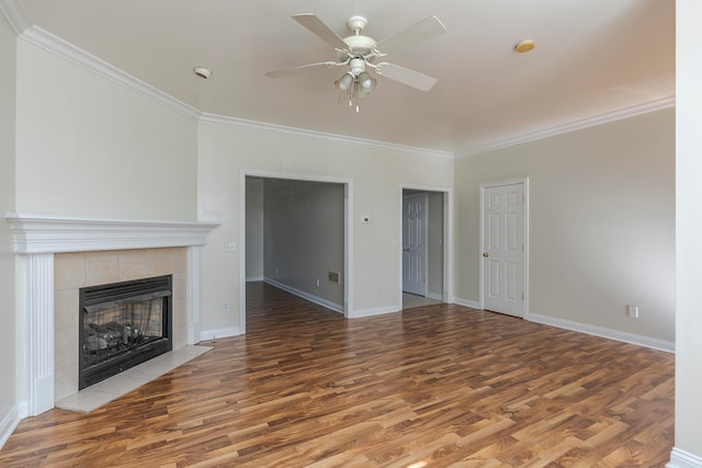 unfurnished living room with crown molding, a tiled fireplace, wood-type flooring, and ceiling fan