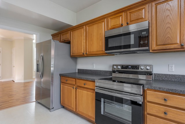 kitchen featuring ornamental molding, stainless steel appliances, and light wood-type flooring