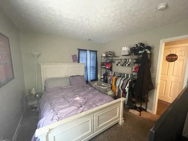 bedroom with a closet, a textured ceiling, and dark colored carpet