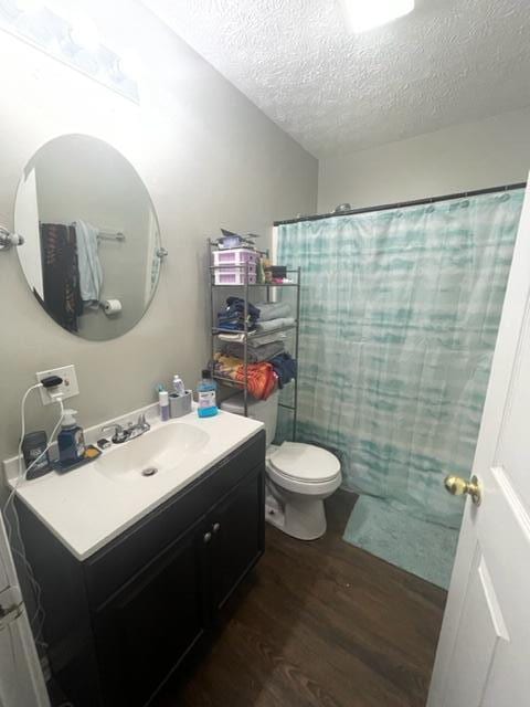 bathroom with a textured ceiling, hardwood / wood-style floors, toilet, a shower with curtain, and vanity