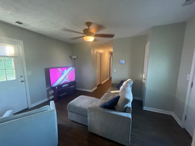 living room with dark hardwood / wood-style floors and ceiling fan