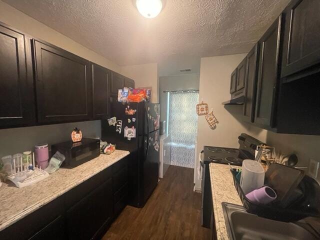 kitchen with sink, dark wood-type flooring, a textured ceiling, and black appliances