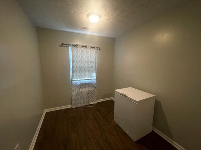 empty room featuring a textured ceiling and dark wood-type flooring