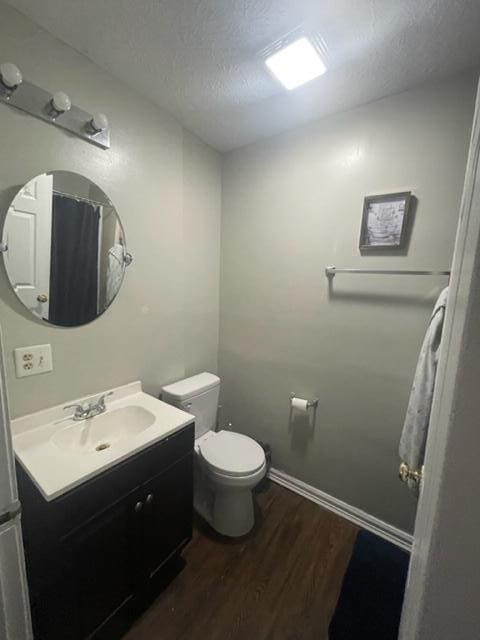 bathroom featuring toilet, a textured ceiling, hardwood / wood-style flooring, and vanity