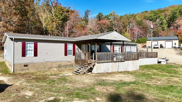 rear view of property featuring a lawn, a garage, covered porch, and an outbuilding