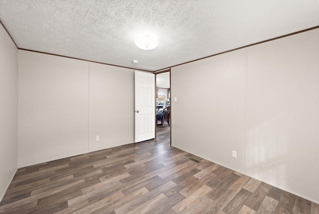 unfurnished room with crown molding, a textured ceiling, and dark wood-type flooring