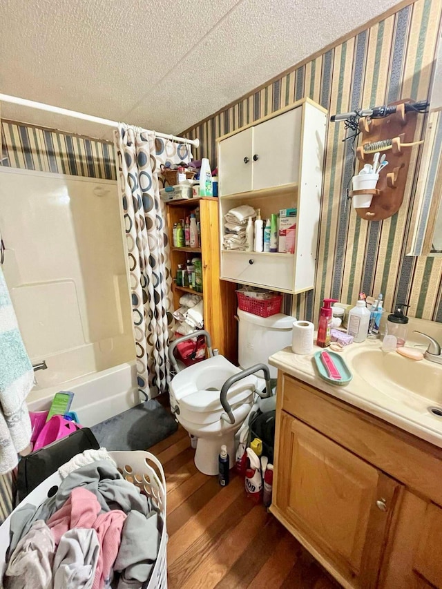 full bathroom featuring hardwood / wood-style flooring, a textured ceiling, shower / bathtub combination with curtain, vanity, and toilet