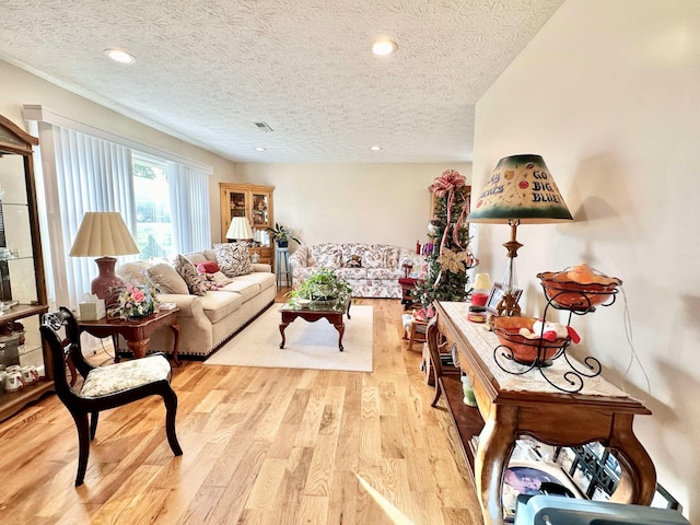 living room featuring recessed lighting, light wood-style floors, visible vents, and a textured ceiling
