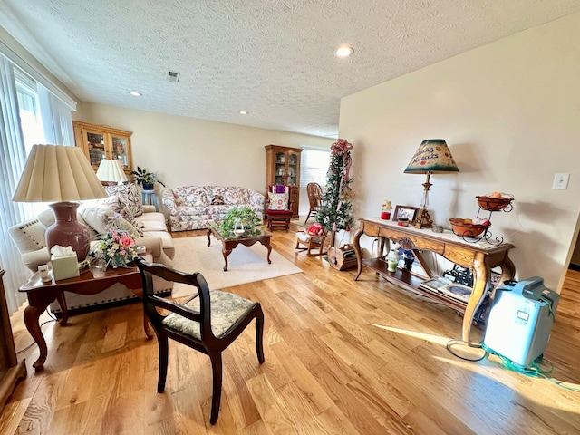 living area featuring recessed lighting, a textured ceiling, light wood finished floors, and visible vents