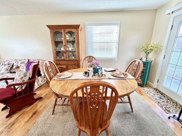 dining area with light hardwood / wood-style flooring and a textured ceiling