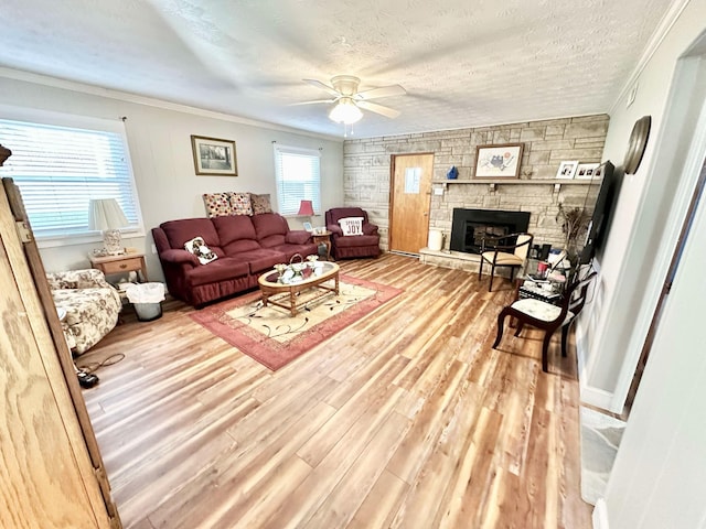 living room with ornamental molding, light hardwood / wood-style flooring, a textured ceiling, and ceiling fan