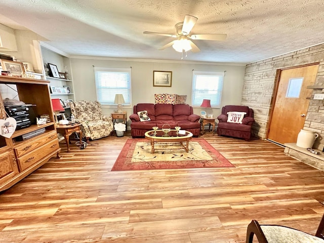 living area with a textured ceiling, a wealth of natural light, a ceiling fan, and light wood-type flooring