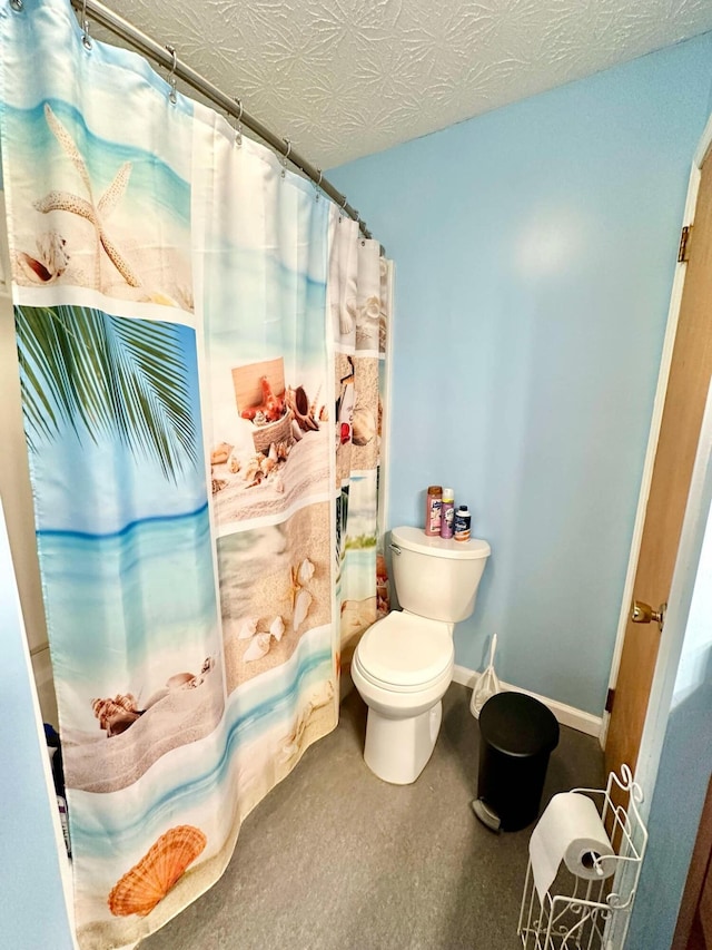 bathroom with toilet, curtained shower, baseboards, and a textured ceiling