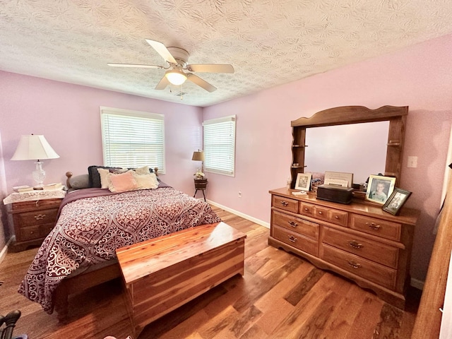 bedroom featuring baseboards, a textured ceiling, light wood-style floors, and ceiling fan