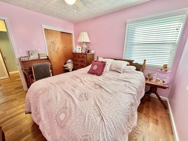 bedroom featuring a closet, wood finished floors, a textured ceiling, baseboards, and ceiling fan
