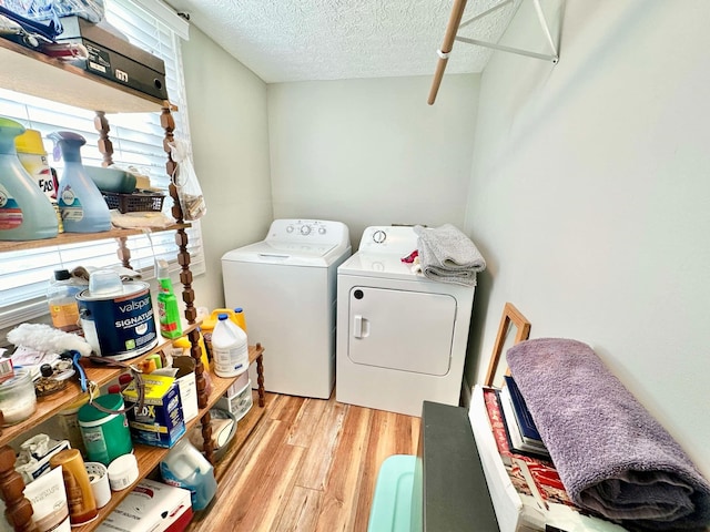 laundry area featuring a textured ceiling, wood finished floors, laundry area, and separate washer and dryer