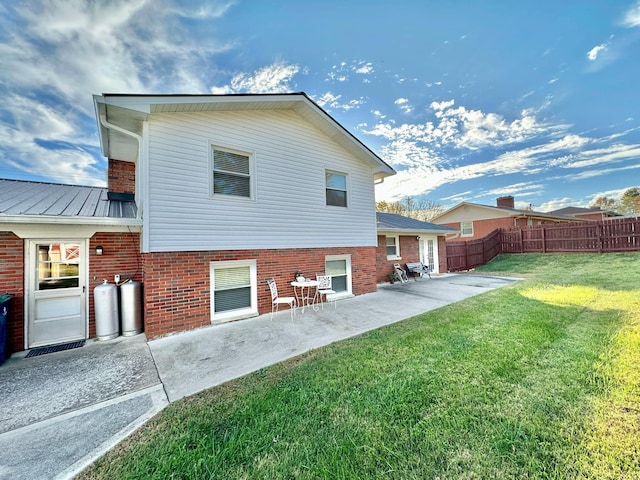 rear view of property featuring a patio area, fence, brick siding, and a yard