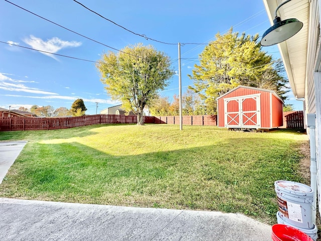 view of yard featuring an outdoor structure, a fenced backyard, and a storage unit