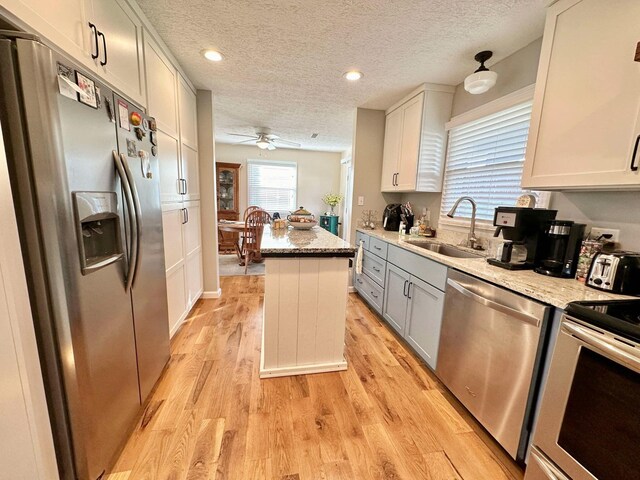 kitchen featuring light stone countertops, a center island, stainless steel appliances, and white cabinets