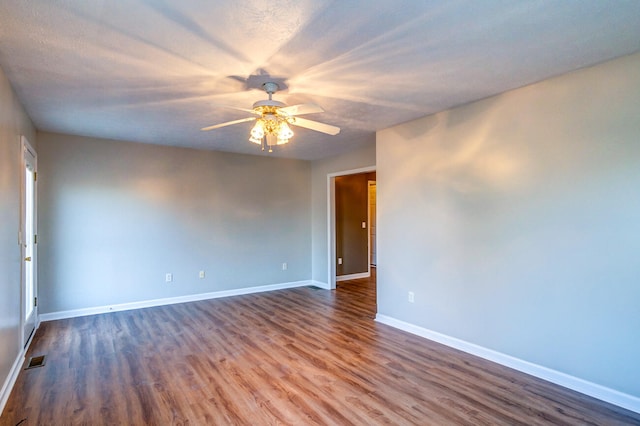 empty room with a textured ceiling, ceiling fan, and dark hardwood / wood-style flooring