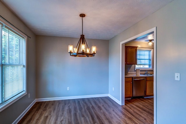 unfurnished dining area featuring an inviting chandelier, a healthy amount of sunlight, and dark hardwood / wood-style flooring